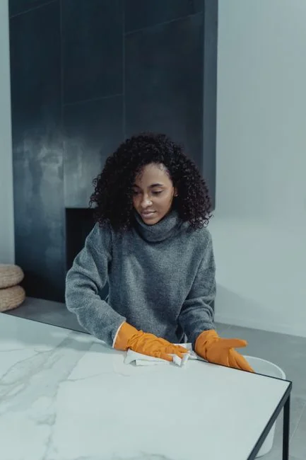 A couple wrapping furniture in a bright apartment, preparing to move.